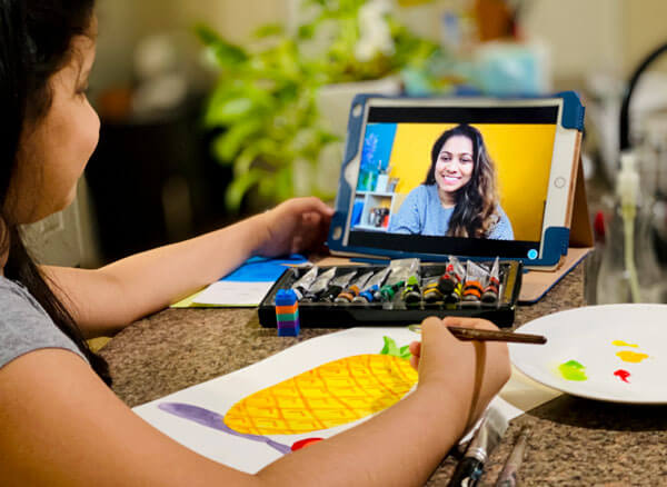 A young child following an online art session from Nimmys art