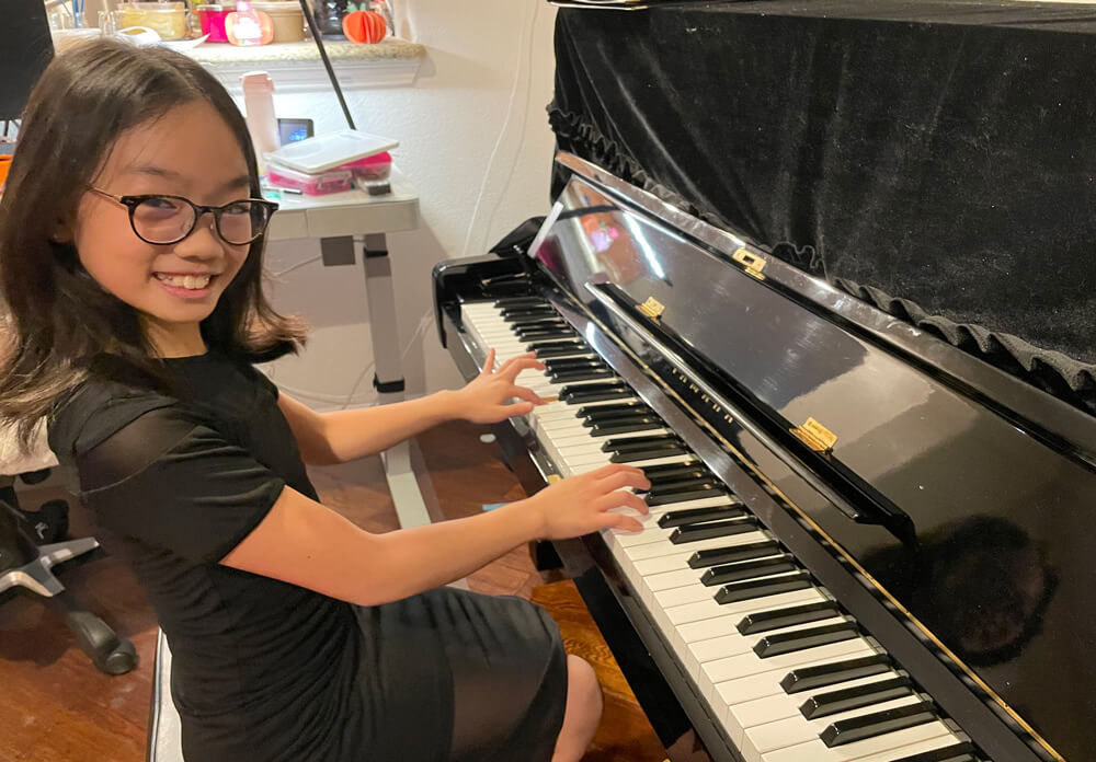 Abigail playing the piano and smiling while striking a pose