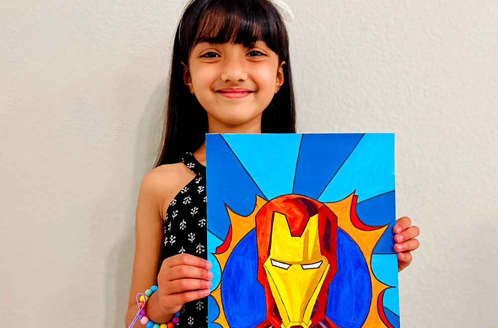 young artist proudly holding her Ironman Pop Art masterpiece