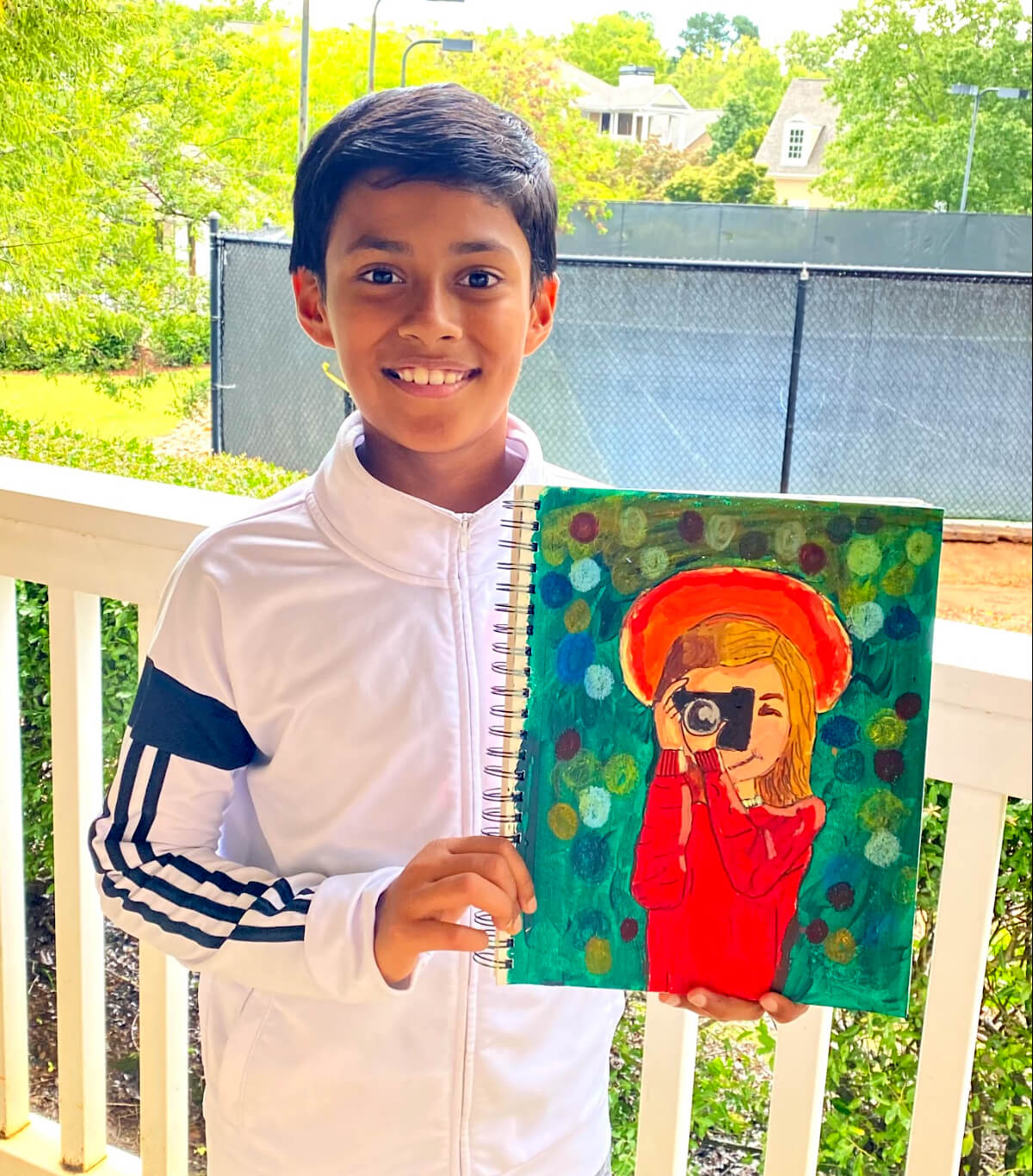 Young artist smiling and holding his acrylic painting titled "Say Cheese!