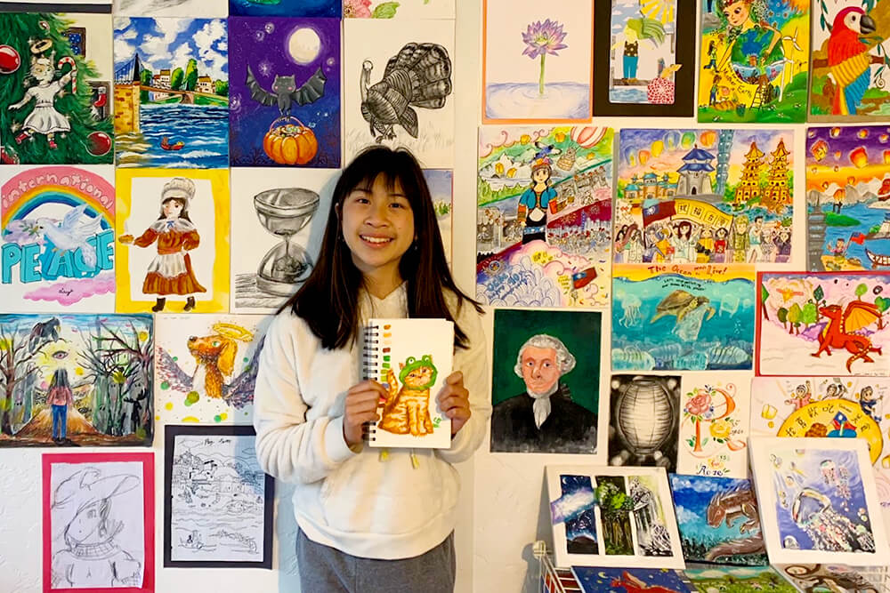 A smiling creative kid artist proudly displaying her colorful and creative art pieces for everyone to admire.