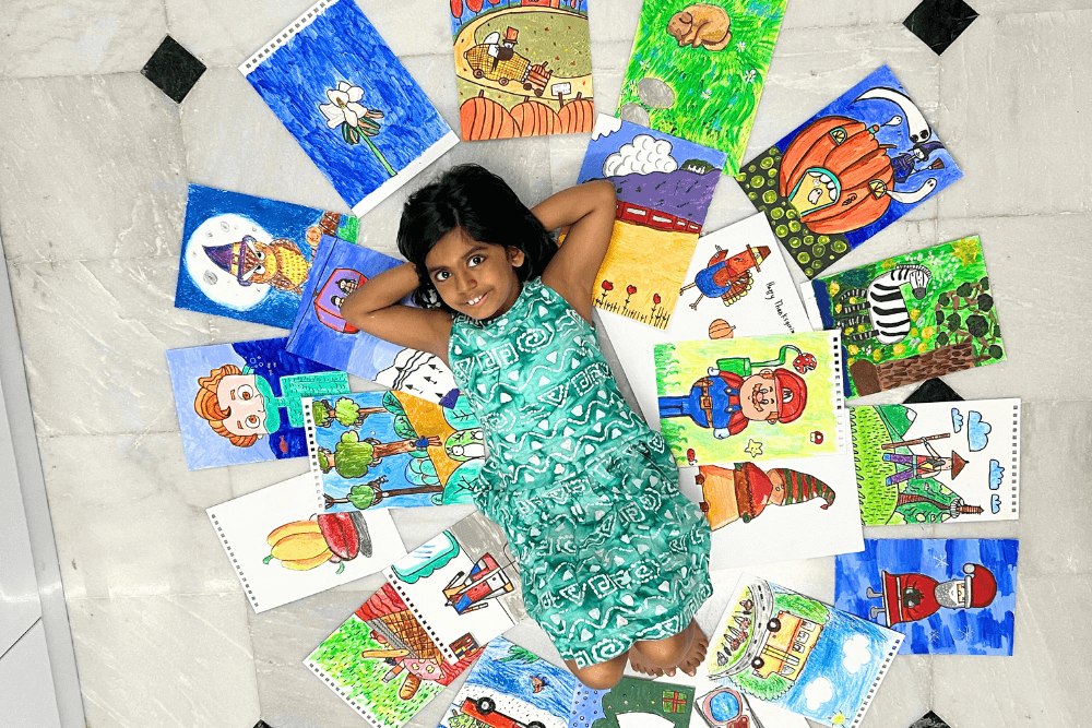 A talented girl surrounded by a vibrant gallery of her own paintings, showcasing the artistic brilliance nurtured through Nimmy's empowering art classes.