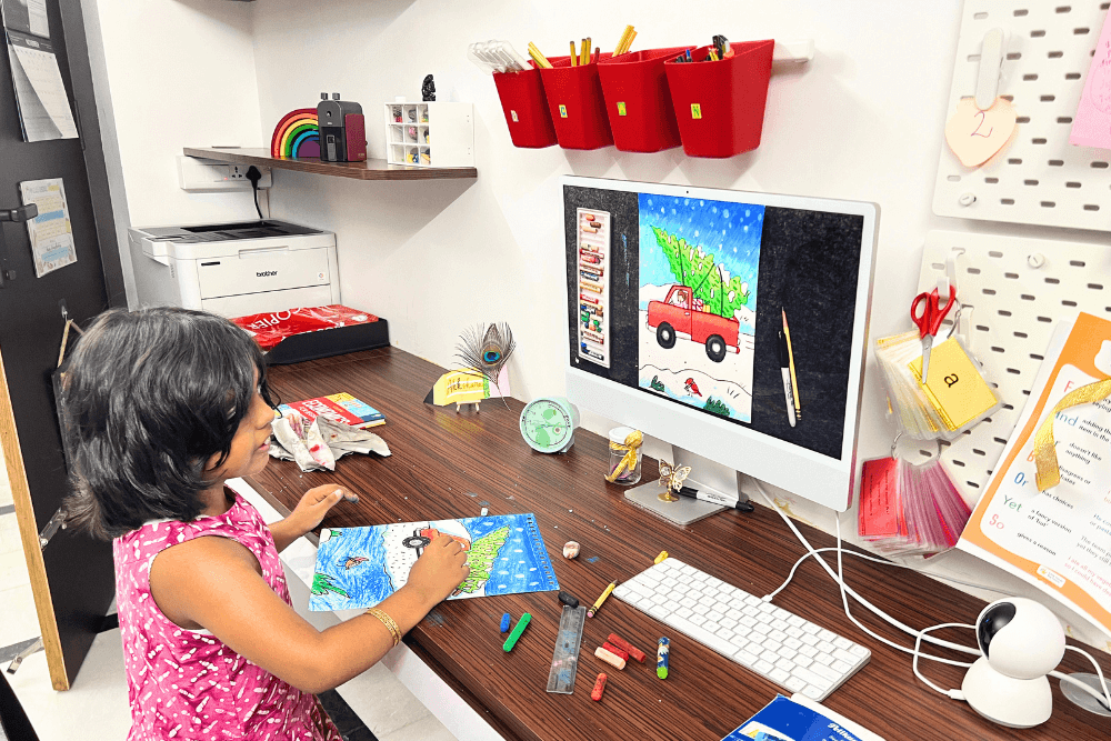 Enthusiastic young artist joyfully painting a Giant Christmas tree in oil pastel during an online art class with her teacher.