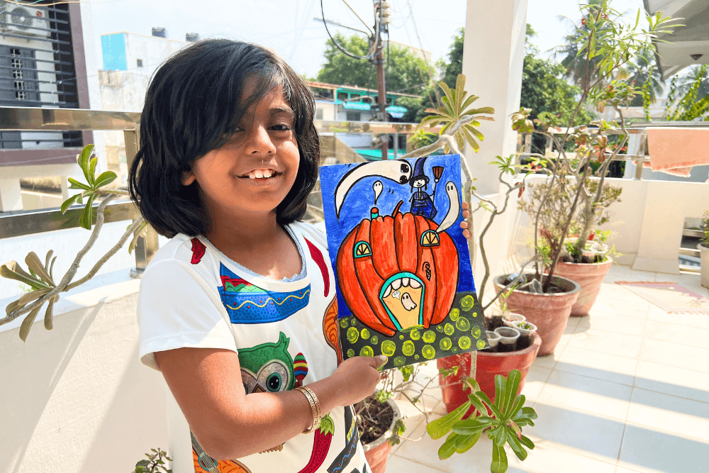 Capture the essence of creativity with this image of a young artist proudly showcasing her hauntingly beautiful acrylic painting titled 'Haunted Pumpkin Castle.' Form Nimmy's Art Online Art Class