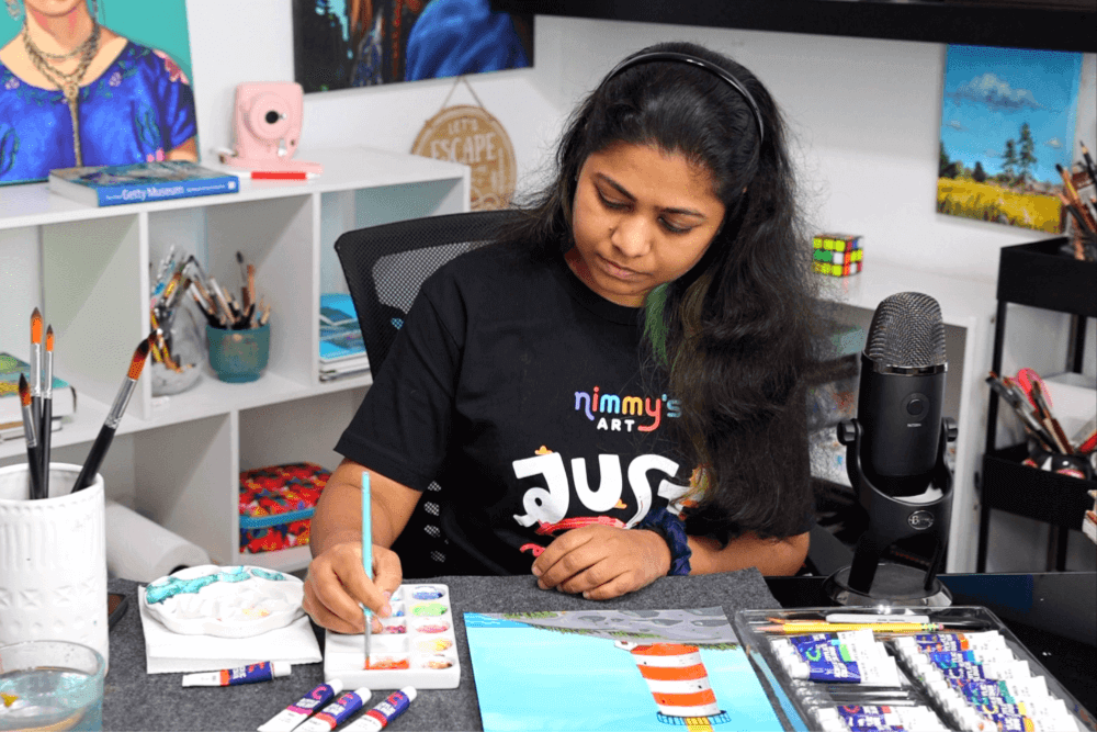Nimmy, an art instructor, painting with vibrant acrylic colors on a canvas.