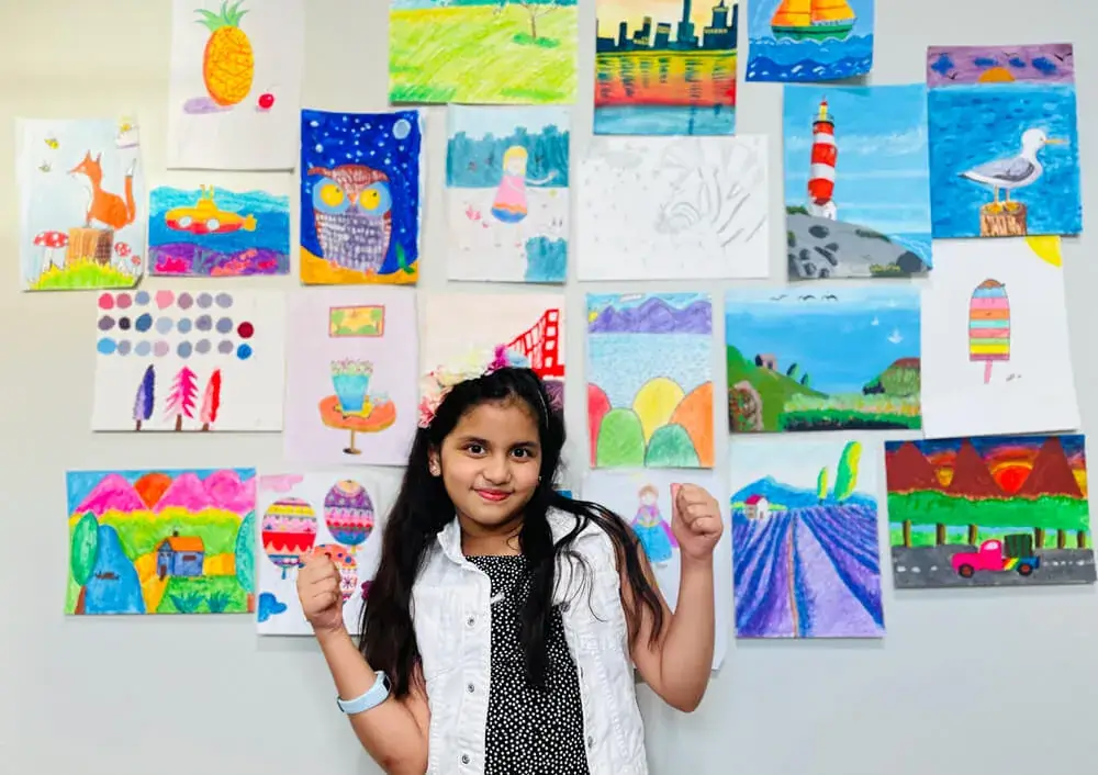 Ardra Ragesh standing with her collage of artworks done at nimmysart