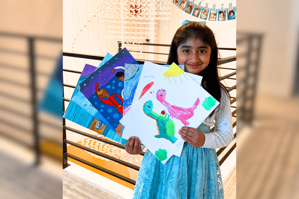 Dhanvi proudly holding her acrylic paintings created during Nimmy’s Art classes.