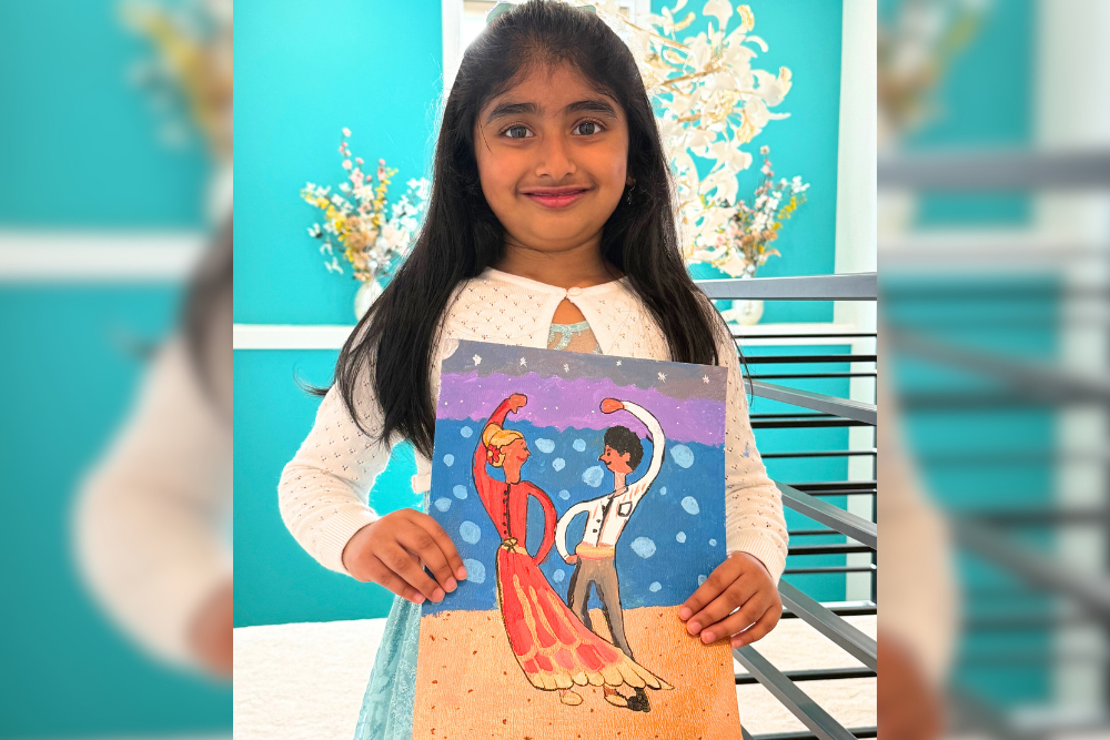 Dhanvi proudly holding her acrylic painting titled “Little Dancers,” featuring graceful figures in motion.