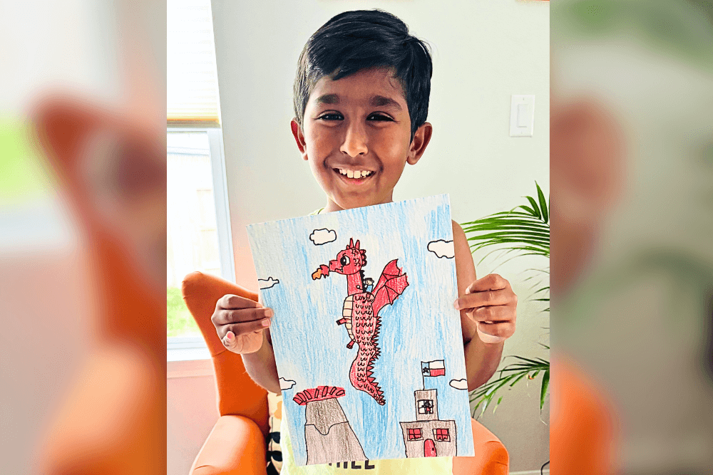 Avyaan holding his pencil drawing of a cute dragon friend, showcasing character study art.
