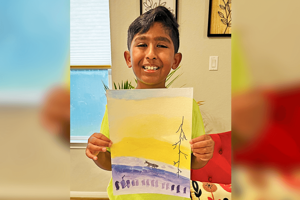 Avyaan holding his watercolor painting of Dawn, created using complementary colors.