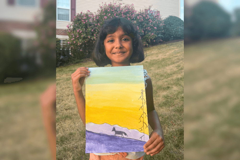 Charvi a little artist holding her watercolor painting titled Dawn, showing a sky in complementary colors. From summer art camp.