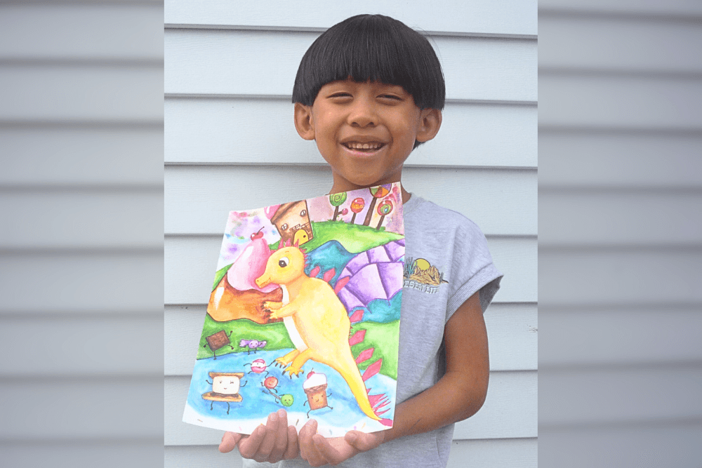 Gareth holding his pencil drawing Cute Dragon Friend, a character study of a playful dragon created at Summer Art Camp 2025.