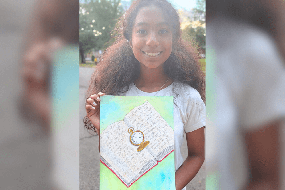 Harene displaying her Prismacolor pencil drawing of an open book with a pocket watch, a still life art study.