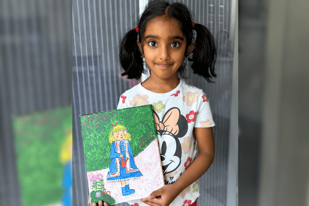 Pranavi holding her acrylic painting of A Girl with a Watering Can inspired by Renoir, created at Summer Art Camp 2025.