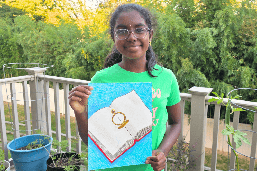 Sananda holding her Prismacolor drawing of a pocket watch resting on an open book.