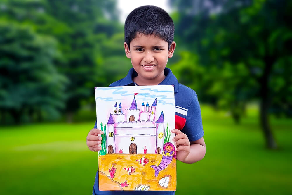 Sarthak, a young artist, proudly holds his acrylic painting titled “Mermaid’s Castle.” The artwork features a magical underwater castle surrounded by colorful fish, ocean plants, seashells, and a friendly mermaid, creating a whimsical scene beneath the sea.