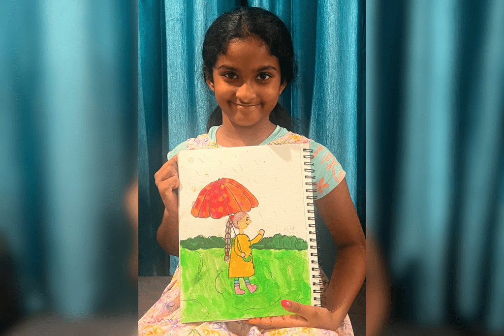Ameya Kolachina holding her rainy-day artwork of a girl with a long braid, yellow raincoat, and red-orange umbrella.