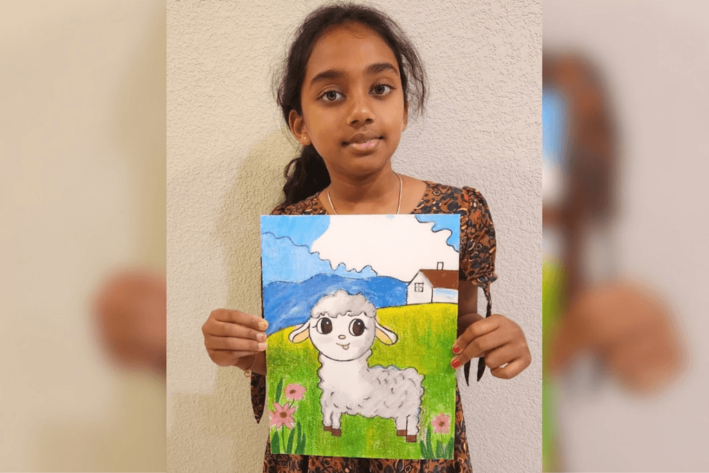 Chathurvi Vasudevan holding her artwork of a fluffy white lamb in a green meadow with pink flowers and blue mountains.